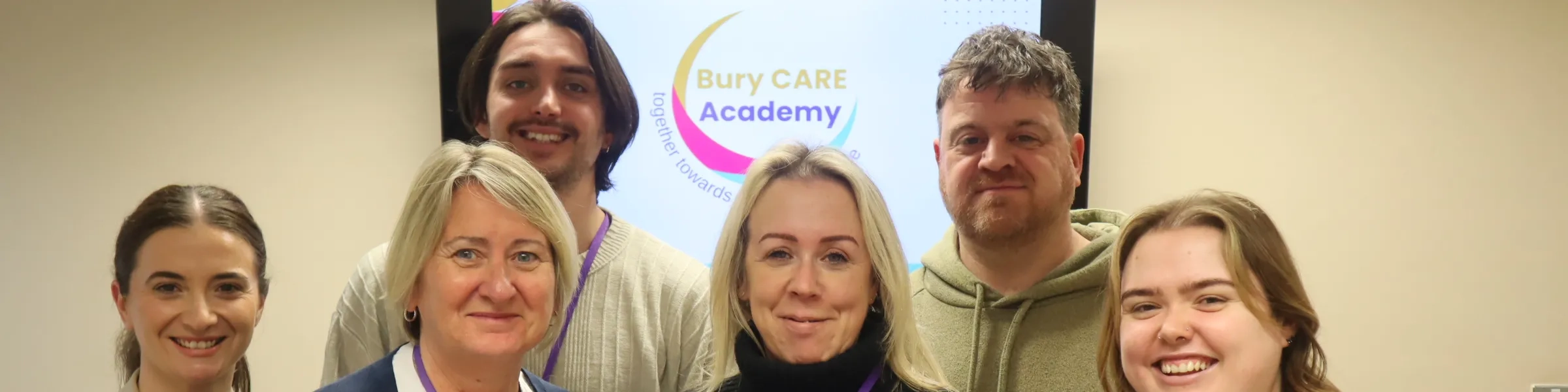 Bury Care Academy team photographed in front on the Bury Care Academy logo