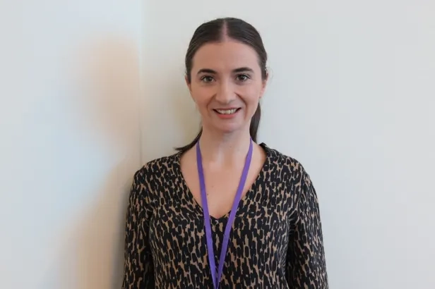 Young woman wearing business casual attire smiling.