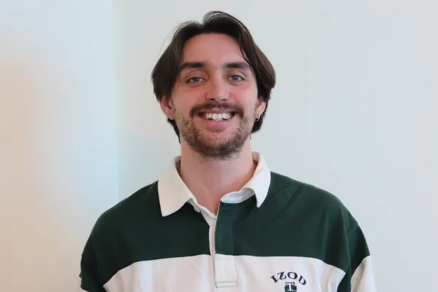 Young male in business casual smiling.