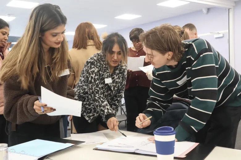 a group of young care workers together stood around a table collaborating on a task