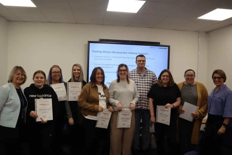 group of care leaders photographed smiling holding up certificates after completing a training programme