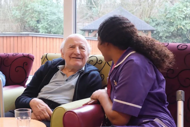 Care worker speaking to resident, both smiling in mid conversation