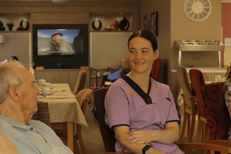 young care worker photographed smiling and chatting to elderly resident