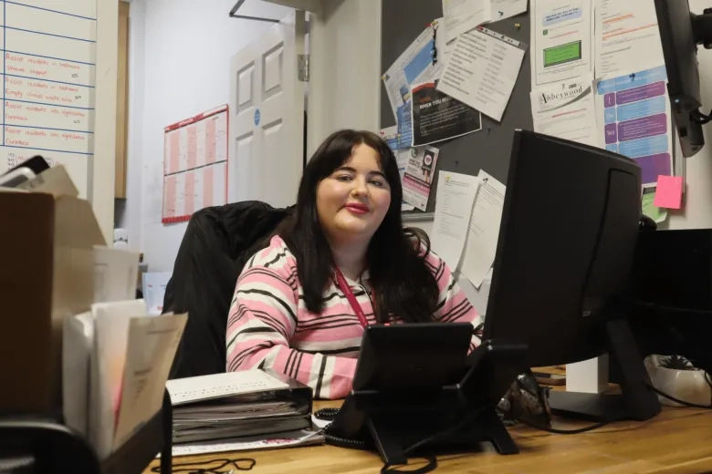 Senior care staff member pictured smiling behind a desk