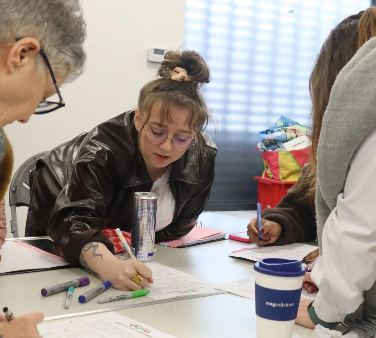 Participants on the LEAD Programme working together writing on a task, one member of the group writes answers on a sheet of paper