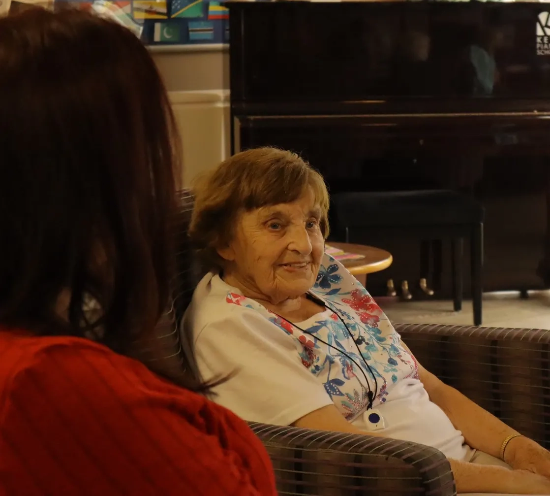 Older adult resident smiling while receiving support in a care setting.