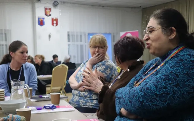 Side angle shot of attendees at the fair sat at a table smiling and speaking to each other