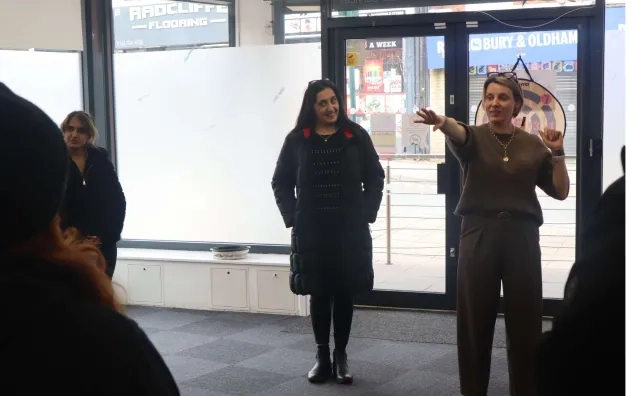 Lead trainer on the LEAD Programme gestures to the group who are all stood in a circle