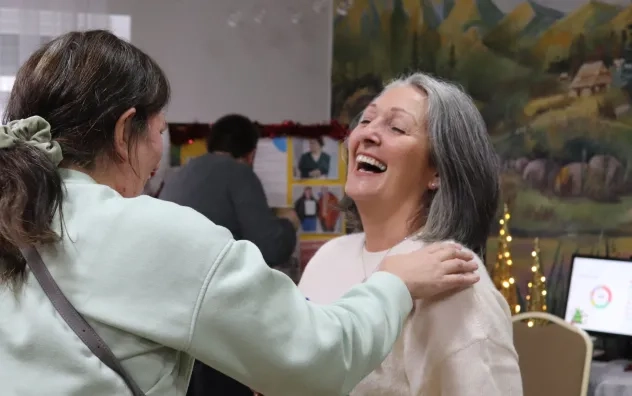 a woman is pictured laughing at the fair as another person with their back turned placed their hand on the woman