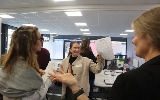 Over the shoulder shot showing a participant of the LEAD programme smiling and lifting a bingo sheet to the presenter