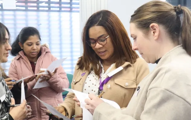 Members of the LEAD Programme stood up looking at pieces of paper, working on a group task together