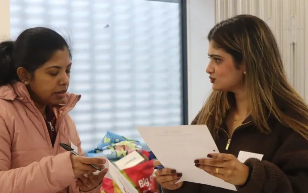 Two members of the LEAD Programme stood discussing answers to a group task