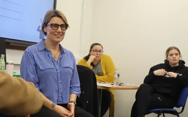 LEAD Programme trainer smiling to someone off camera as the group engage in a discussion, other attendees can be seen in the background also listening