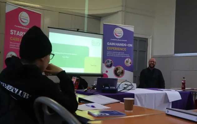 Head of Safeguarding at Bury Council smiles and looks towards an attendee who is engaging with him in a discussion